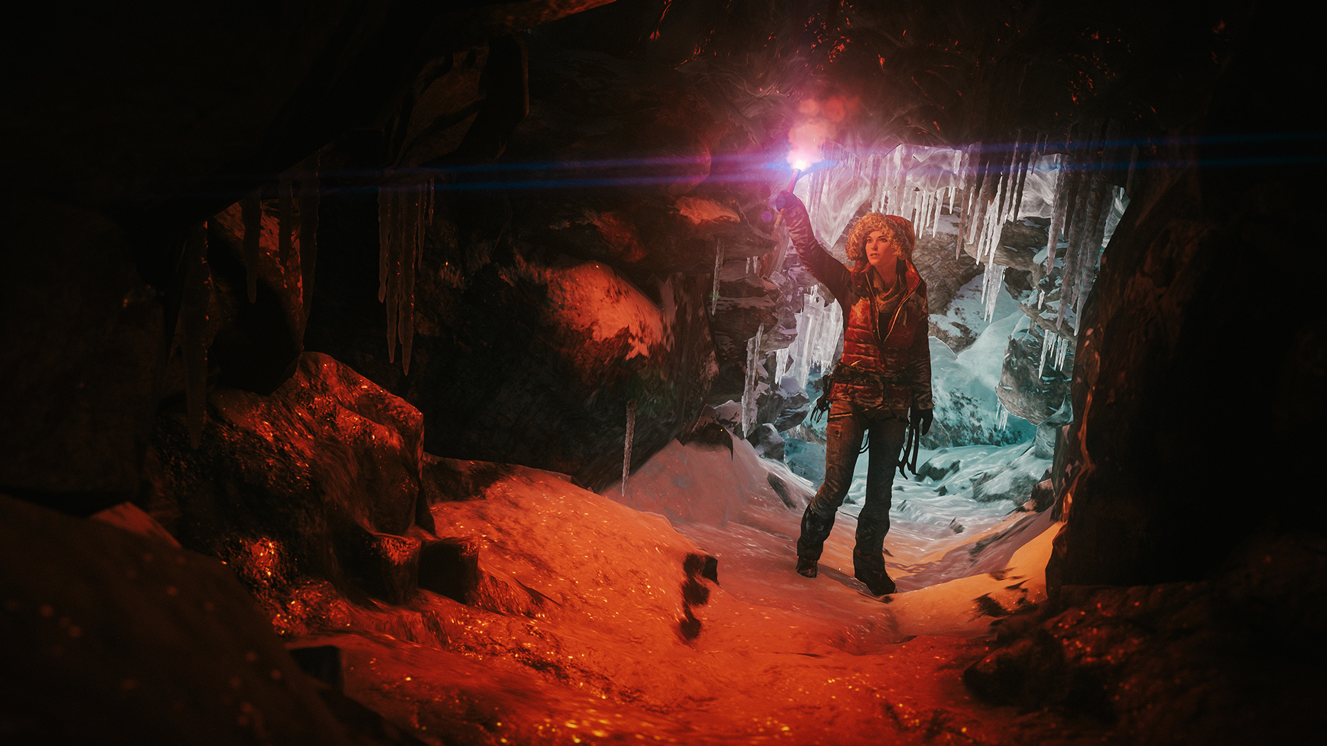 Lara Croft com um sinalizador aceso em uma caverna de gelo, com estalactites e paredes iluminadas de vermelho